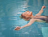 Woman floating peacefully in a clear blue pool