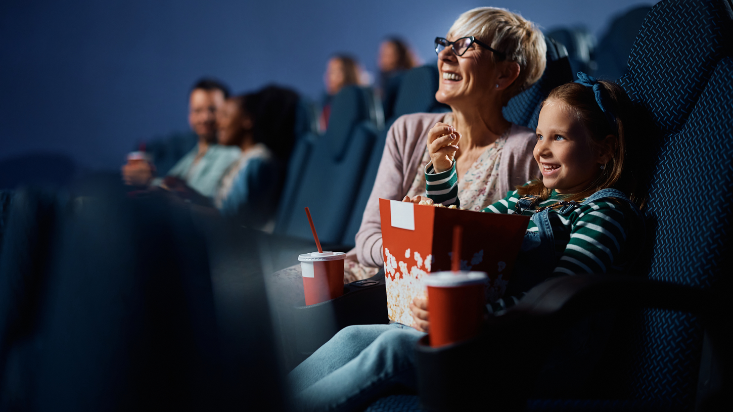 Grandmother and granddaughter enjoying a movie together with popcorn