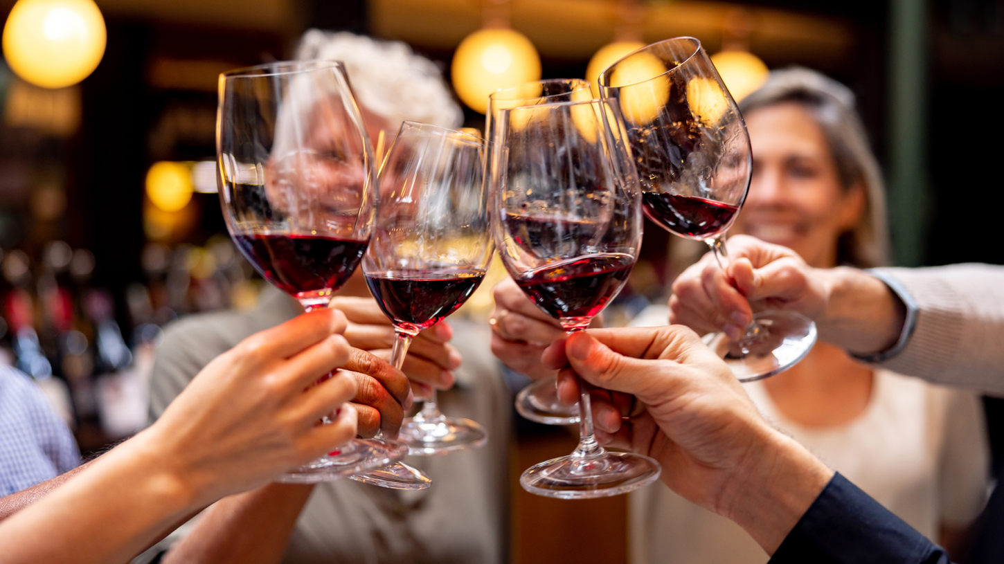 Group of people toasting with red wine glasses at a social gathering