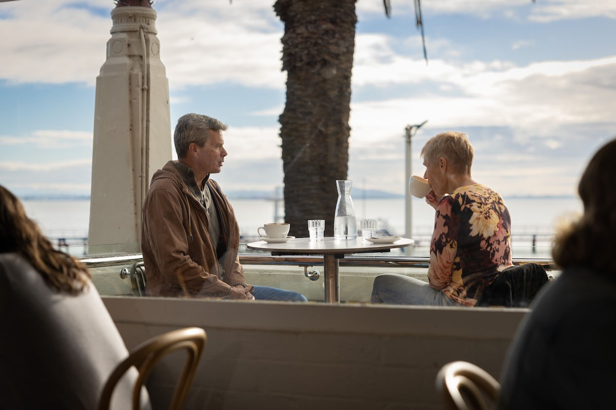 Two people enjoying an outdoor seaside dining experience with ocean views