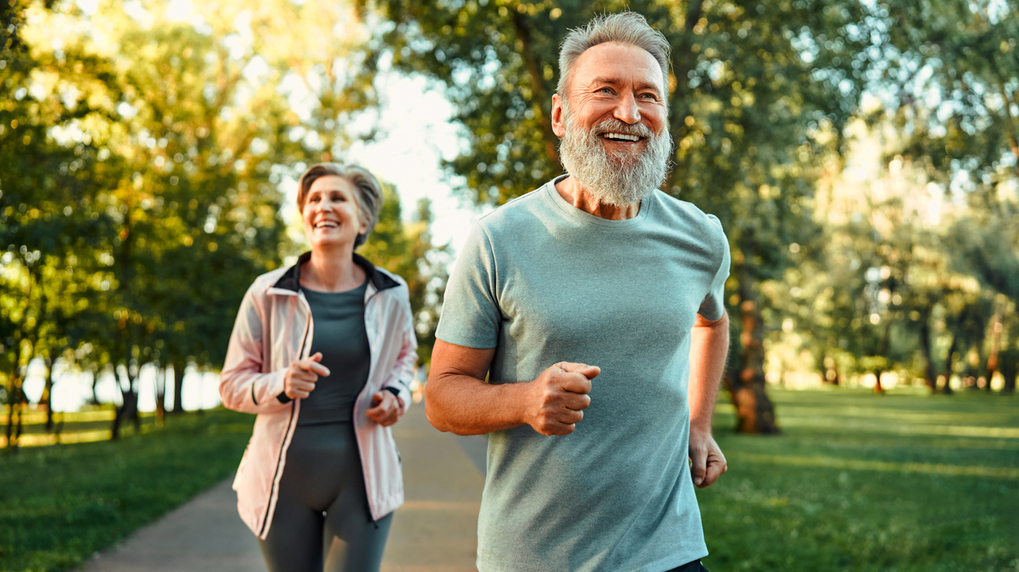Senior couple jogging together in a sunny park